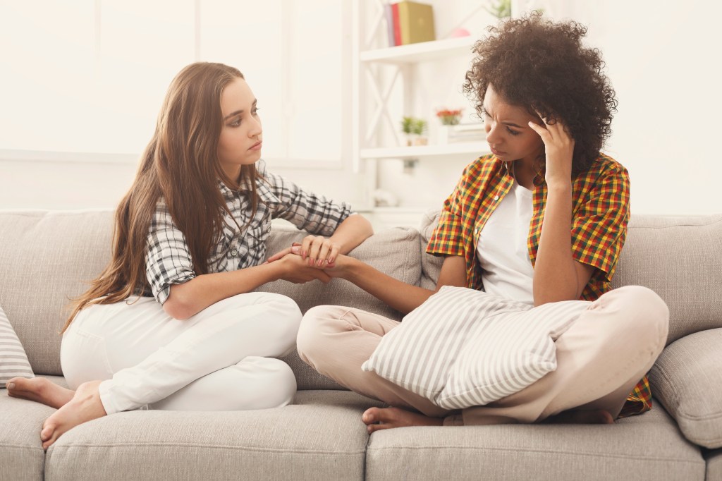 Mulheres sentadas no sofá com expressão de preocupação e empatia pela outra