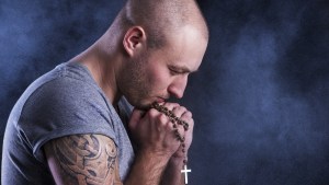 Homem rezando terço