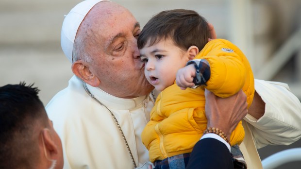 Pope Francis Kisses a child at the end of his weekly general audience in St. Peter's square