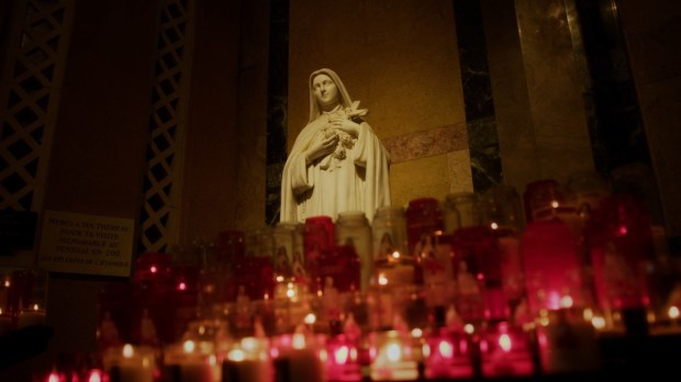 Estátua de Santa Teresinha cercada de velas
